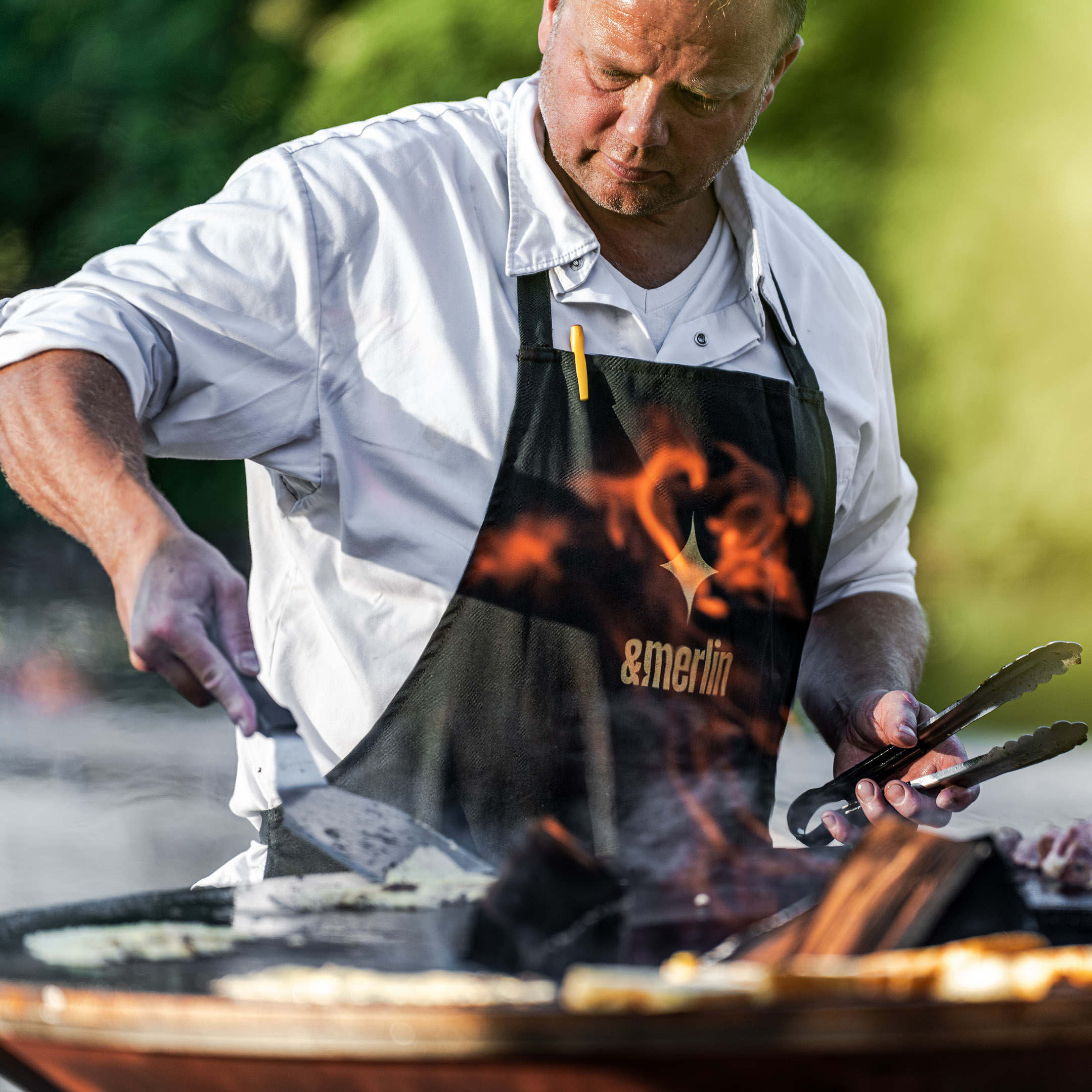 Chef cooking on an OFYR grill at an &merlin event