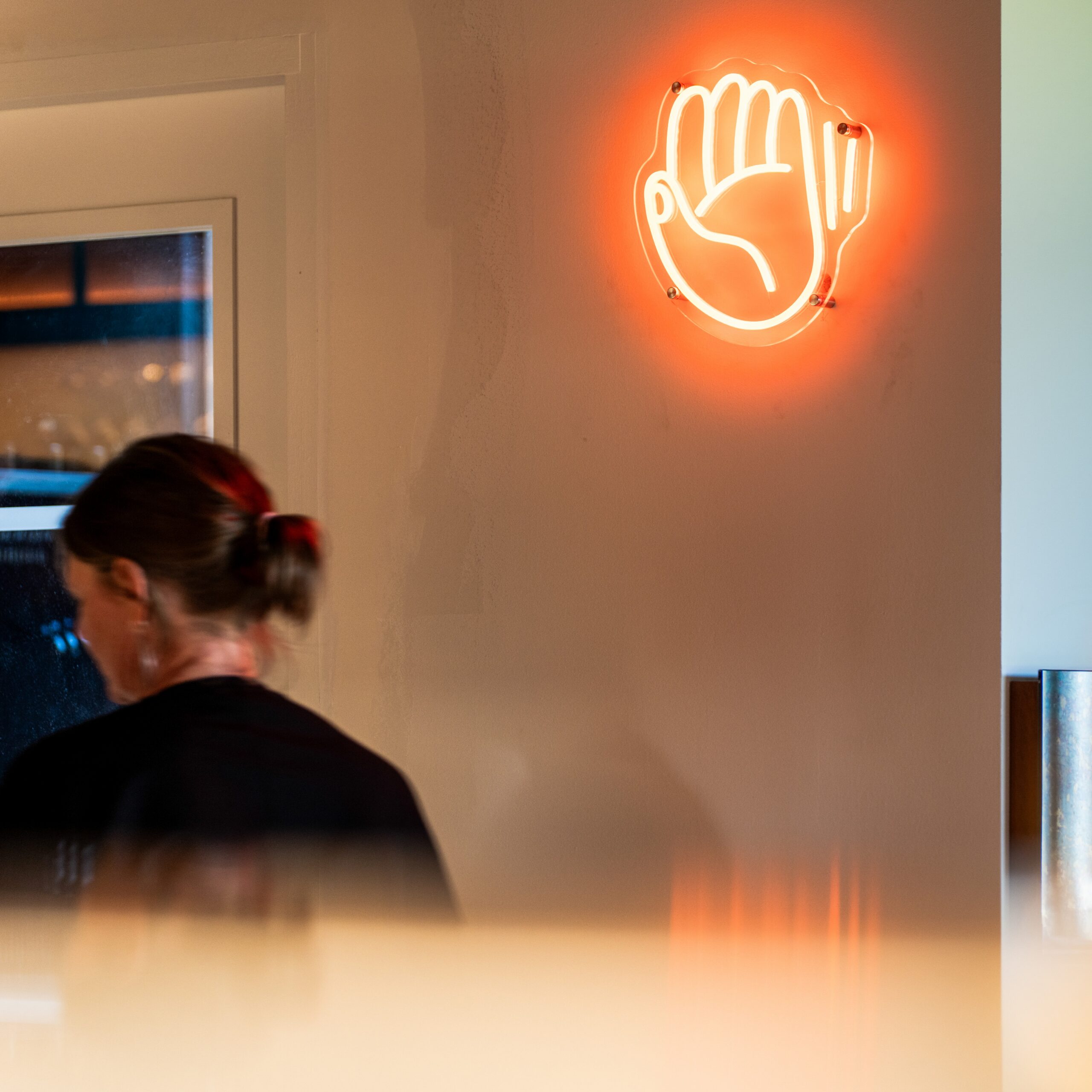 Orange neon hand sign in the De Achterdeur interior